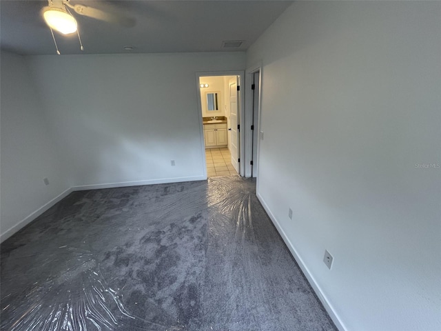 unfurnished bedroom with ensuite bath, baseboards, ceiling fan, and carpet flooring