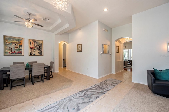 dining room featuring ceiling fan with notable chandelier, tile flooring, and a raised ceiling