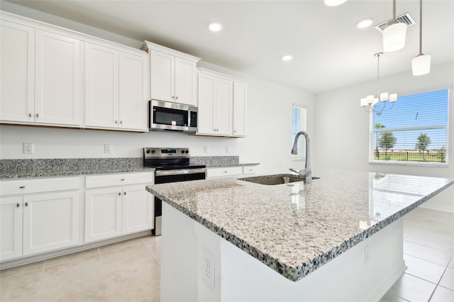 kitchen with white cabinets, stainless steel appliances, hanging light fixtures, and a kitchen island with sink