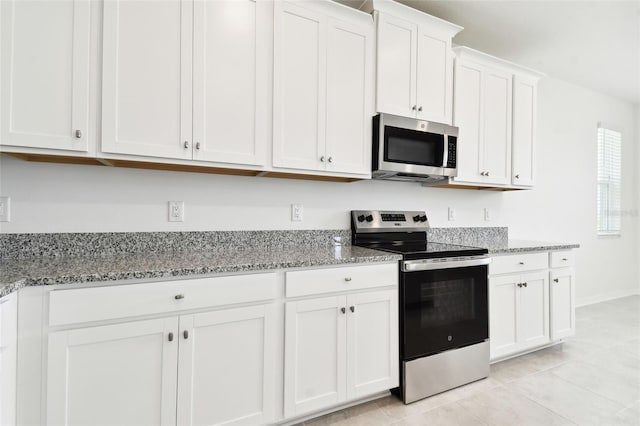 kitchen with white cabinetry, light tile patterned flooring, light stone counters, and appliances with stainless steel finishes