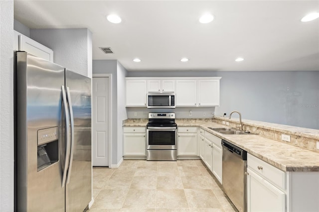 kitchen featuring light tile patterned floors, kitchen peninsula, white cabinets, stainless steel appliances, and sink