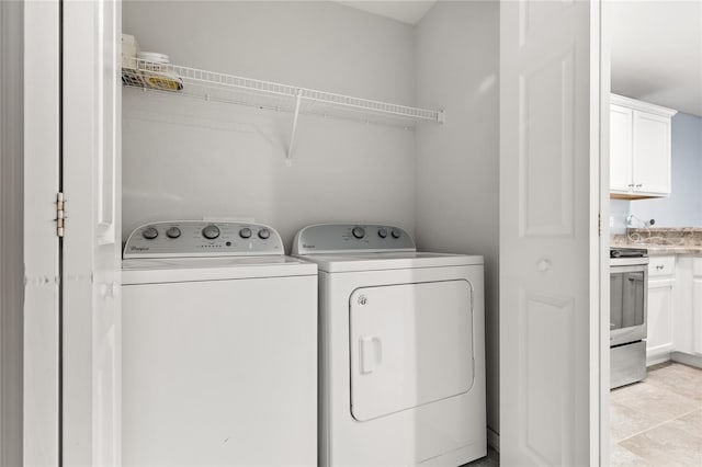 clothes washing area with washer and dryer and light tile patterned floors