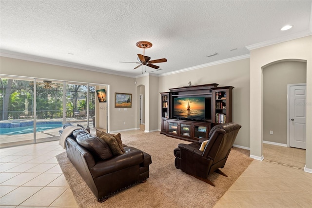 living room featuring a textured ceiling, ceiling fan, light tile floors, and ornamental molding