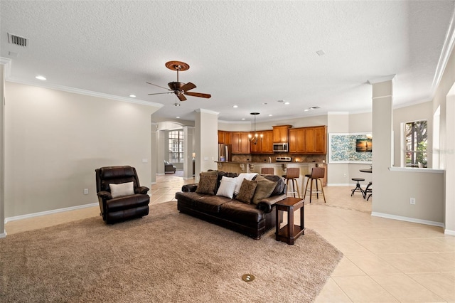 tiled living room with a textured ceiling, ceiling fan, and crown molding