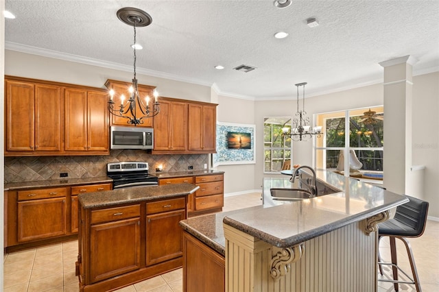 kitchen with decorative light fixtures, a center island with sink, appliances with stainless steel finishes, and light tile flooring