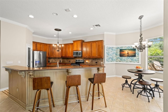 kitchen with hanging light fixtures, stainless steel appliances, an inviting chandelier, and light tile floors