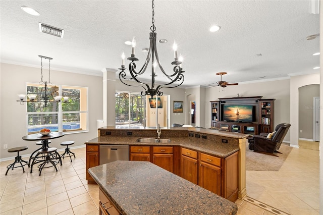 kitchen with pendant lighting, light tile flooring, crown molding, stainless steel dishwasher, and a center island with sink