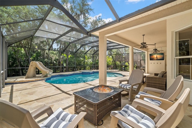 view of swimming pool with a patio area, ceiling fan, a water slide, glass enclosure, and an outdoor living space