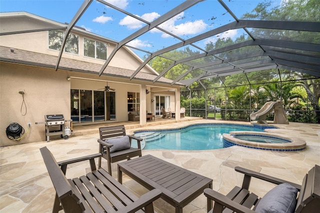 view of swimming pool with a patio, a lanai, an in ground hot tub, a water slide, and ceiling fan