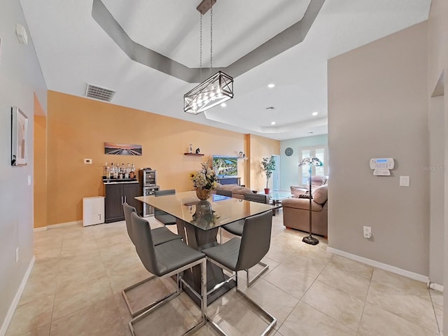 dining area featuring light tile patterned flooring, bar area, and a tray ceiling