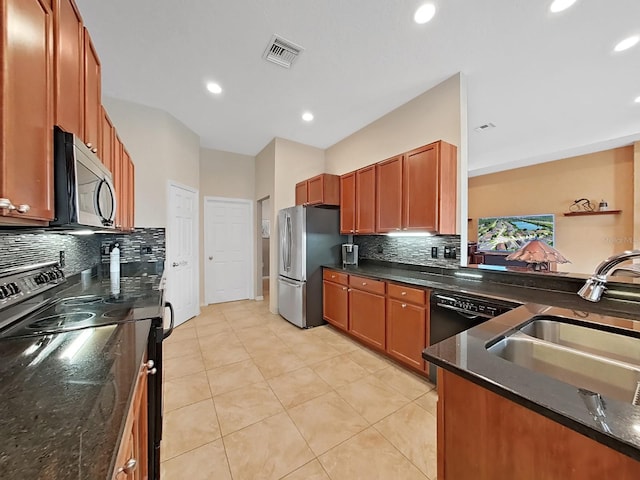 kitchen featuring sink, light tile patterned floors, stainless steel appliances, and dark stone counters