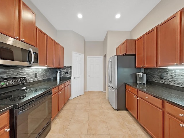 kitchen with dark stone countertops, light tile patterned floors, decorative backsplash, and appliances with stainless steel finishes