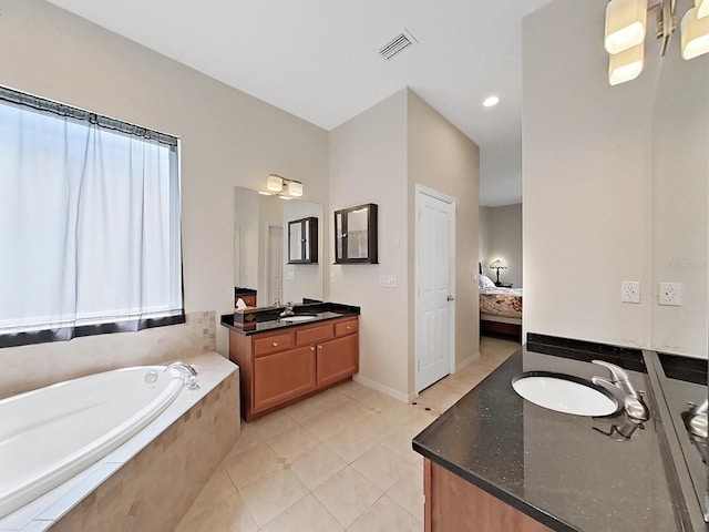 bathroom with tile patterned floors, vanity, and tiled bath