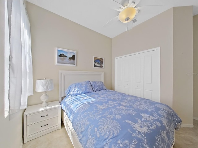 bedroom featuring light carpet, ceiling fan, and a closet