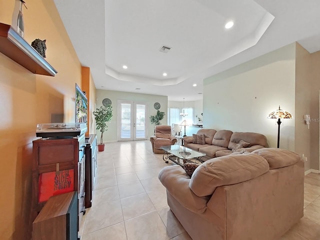 tiled living room with a raised ceiling and french doors