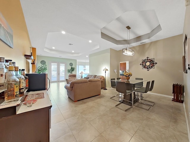 living room featuring french doors, a tray ceiling, and light tile patterned floors