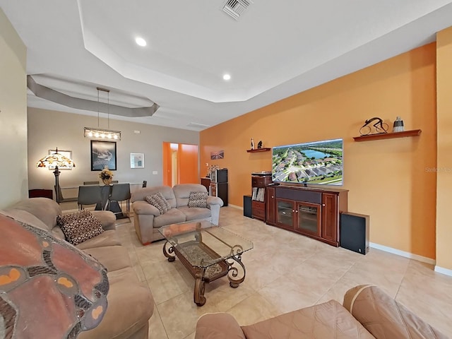 living room with light tile patterned flooring and a tray ceiling