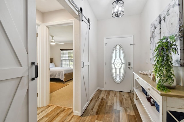 foyer with ceiling fan, light wood-type flooring, and a barn door