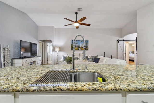 kitchen featuring white cabinets, vaulted ceiling, sink, and ceiling fan