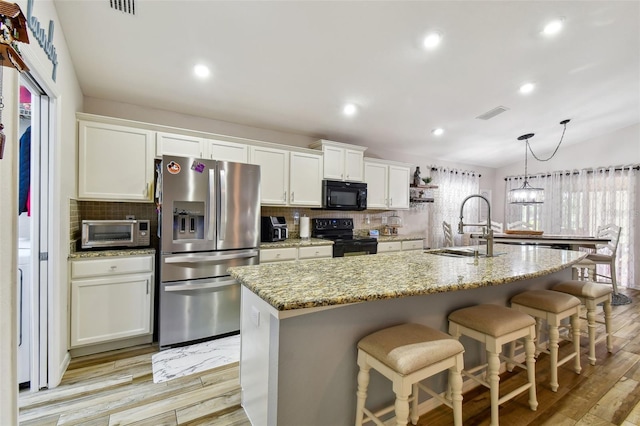 kitchen featuring a center island with sink, black appliances, tasteful backsplash, white cabinets, and sink