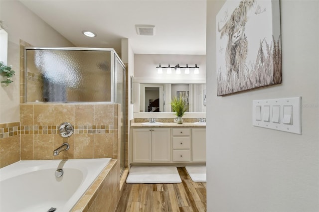 bathroom with dual sinks, wood-type flooring, separate shower and tub, and large vanity