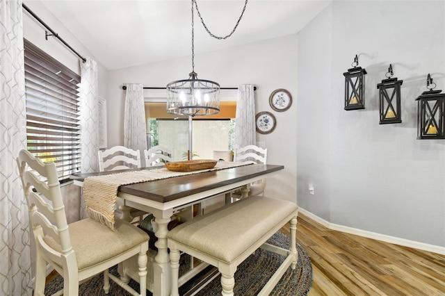 dining space with hardwood / wood-style flooring, a notable chandelier, and lofted ceiling