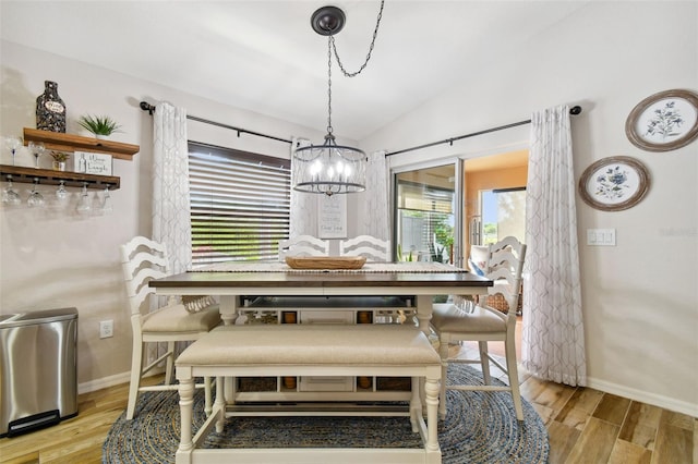 dining space featuring a notable chandelier, light hardwood / wood-style floors, and vaulted ceiling