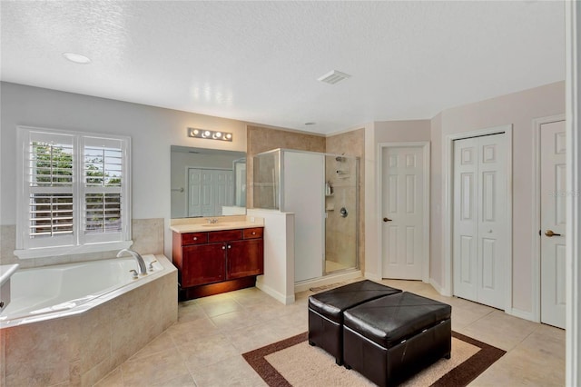 bathroom featuring tile patterned floors, vanity, a textured ceiling, and separate shower and tub