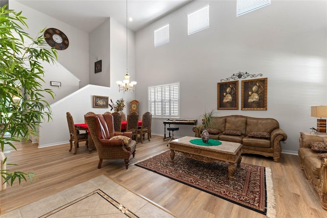 living room featuring a towering ceiling, light hardwood / wood-style floors, and a notable chandelier