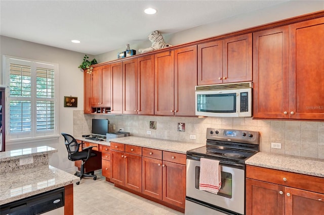 kitchen with backsplash, light stone countertops, built in desk, and stainless steel appliances