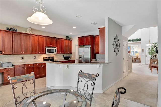 kitchen featuring a kitchen breakfast bar, hanging light fixtures, light stone counters, kitchen peninsula, and stainless steel appliances