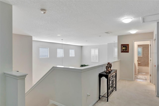 hallway with light colored carpet and a textured ceiling