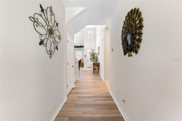 corridor with light hardwood / wood-style floors and a high ceiling