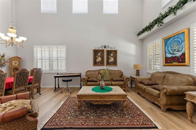 living room with a notable chandelier, light hardwood / wood-style floors, and a high ceiling