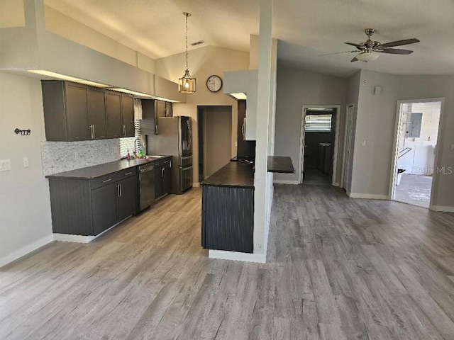 kitchen with dark brown cabinetry, appliances with stainless steel finishes, light wood-type flooring, vaulted ceiling, and decorative backsplash