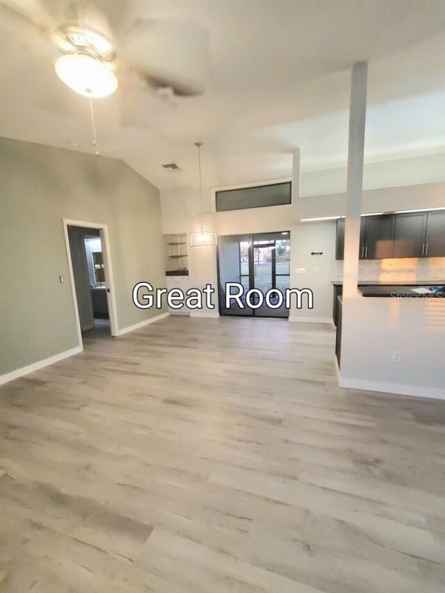 unfurnished living room with lofted ceiling, wood-type flooring, and ceiling fan