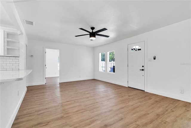 unfurnished living room with light wood-type flooring, baseboards, visible vents, and a ceiling fan