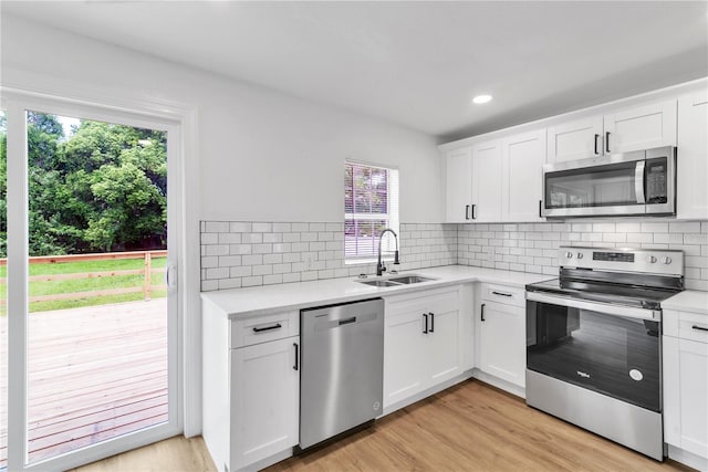 kitchen with stainless steel appliances, a sink, light countertops, and white cabinets