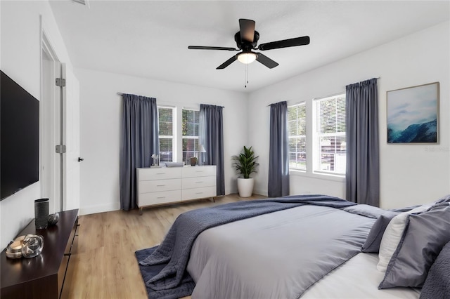 bedroom with light wood-type flooring, ceiling fan, and baseboards