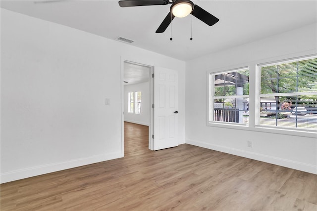 spare room with plenty of natural light, light wood-style flooring, visible vents, and baseboards