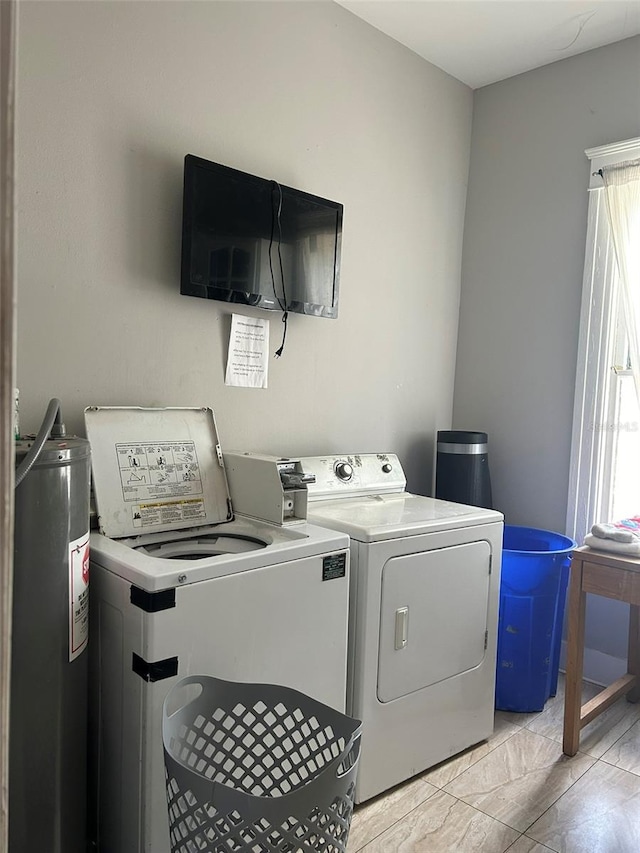 clothes washing area with water heater, light tile flooring, and washing machine and clothes dryer