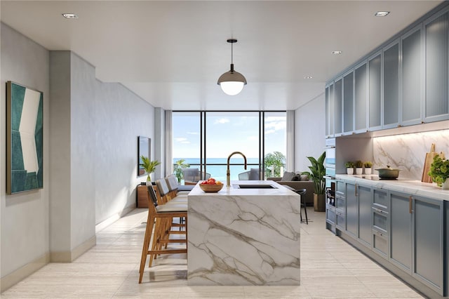 kitchen featuring expansive windows, decorative light fixtures, tasteful backsplash, a kitchen island with sink, and sink