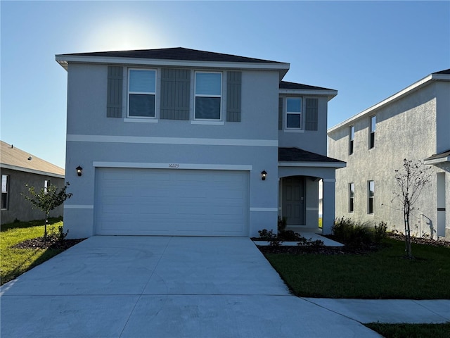 traditional-style house featuring a garage, driveway, a front yard, and stucco siding