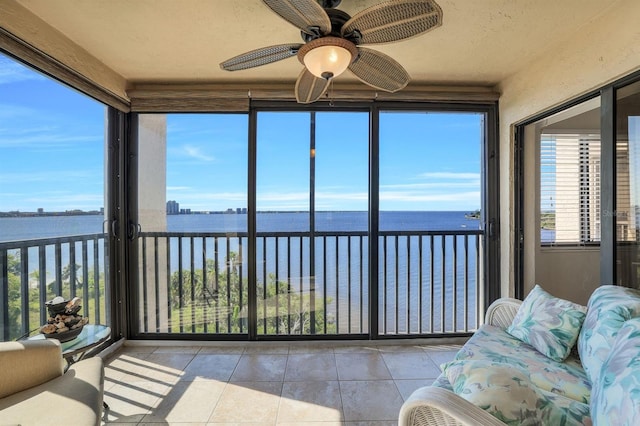 sunroom / solarium with a wealth of natural light, ceiling fan, and a water view