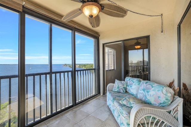 sunroom featuring ceiling fan and a water view