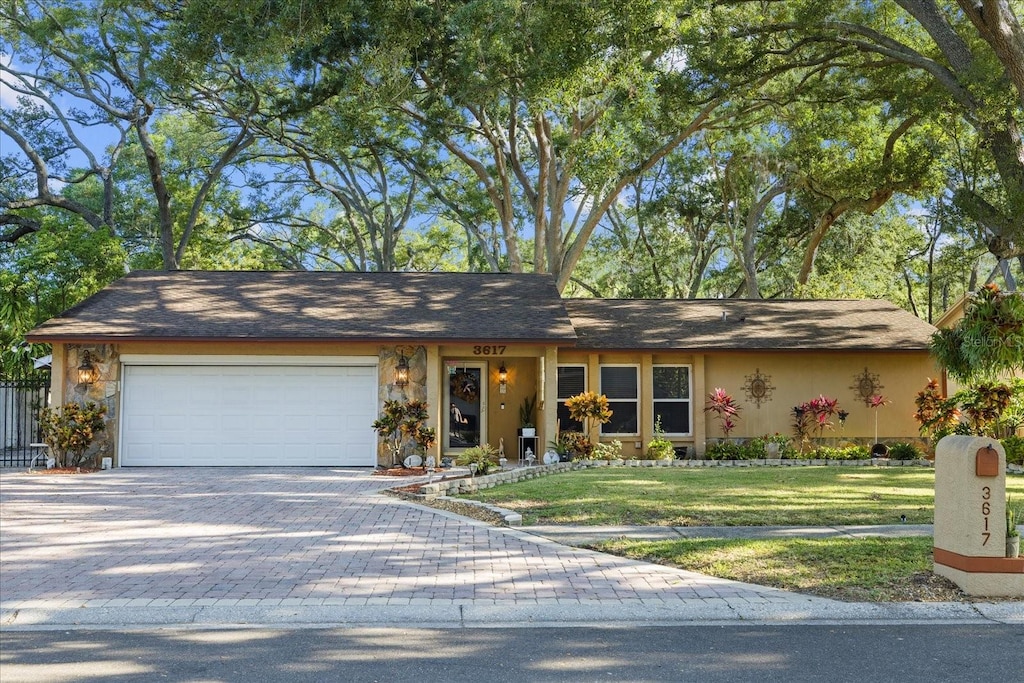 ranch-style home featuring a garage and a front lawn