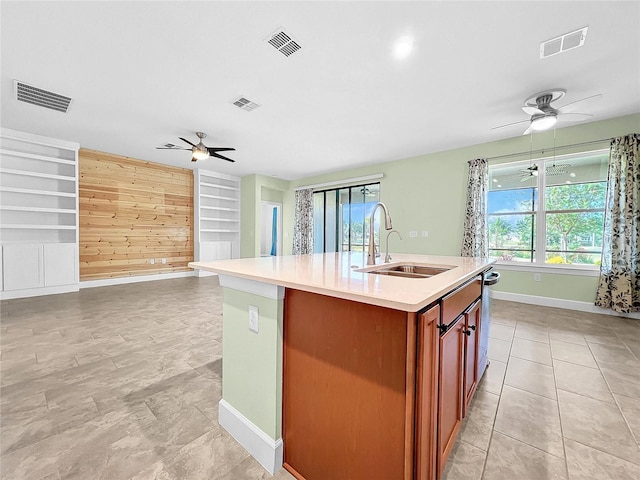 kitchen with light tile patterned flooring, a kitchen island with sink, sink, and ceiling fan