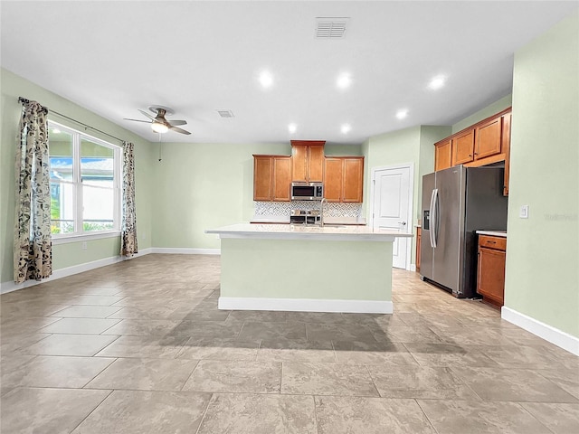 kitchen featuring appliances with stainless steel finishes, an island with sink, light tile patterned floors, and ceiling fan