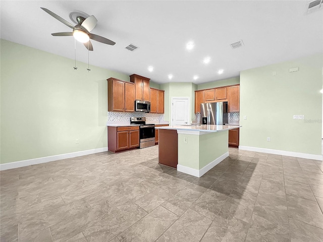 kitchen featuring tasteful backsplash, light tile patterned floors, stainless steel appliances, a kitchen island with sink, and ceiling fan