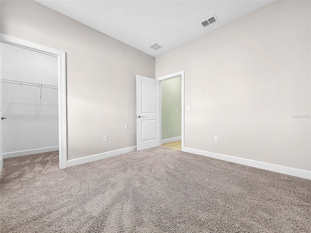 unfurnished bedroom featuring baseboards, visible vents, a spacious closet, and carpet flooring